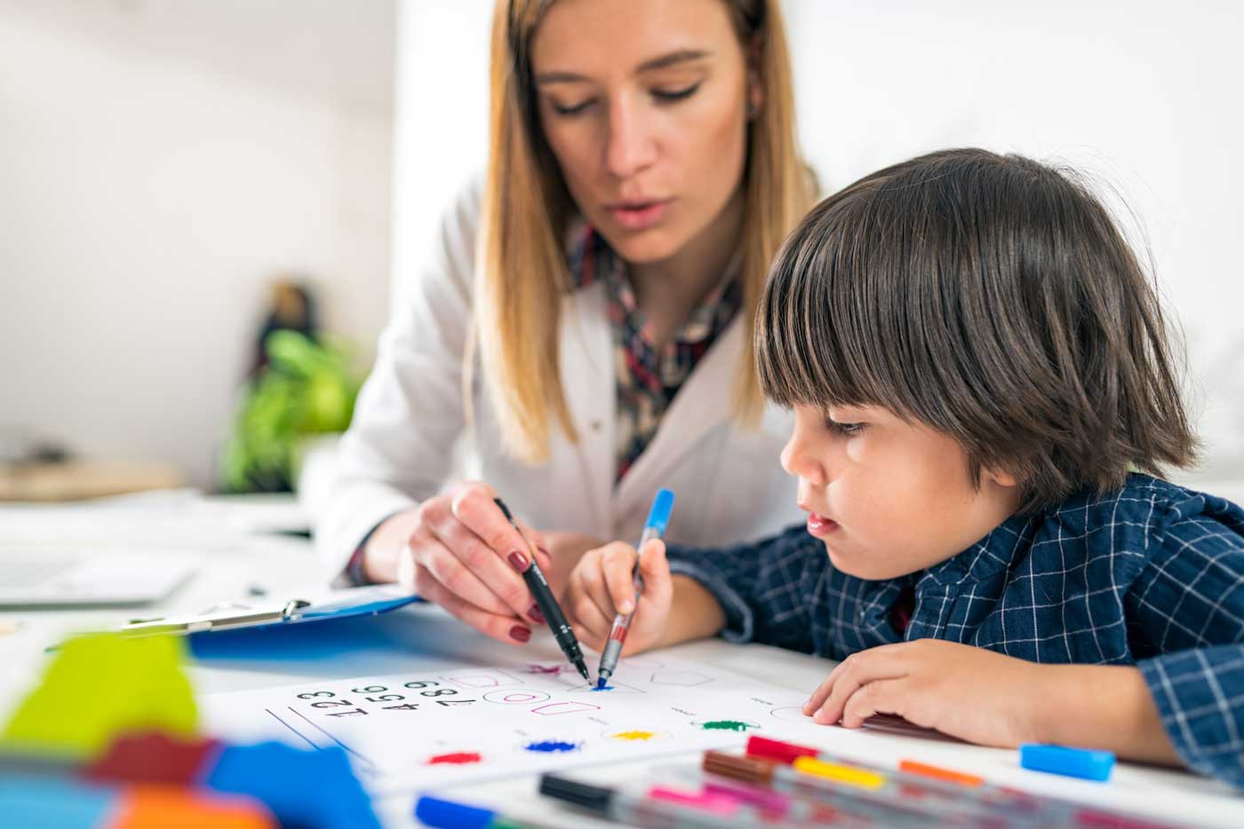 Photograph of child and therapist drawing together
