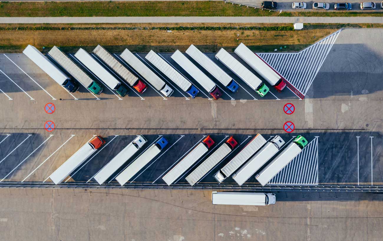 Aerial view of numerous transport trucks parked in parking lot
